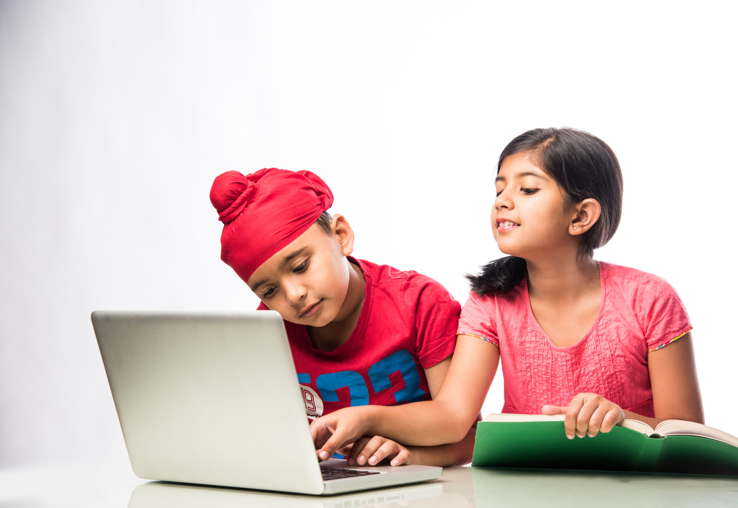 indian sikh/punjabi boy and girl studying with books and laptop computer at study table